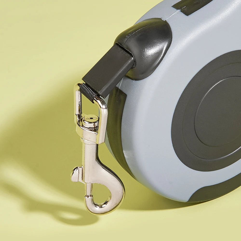 Retractable dog leash with a metallic clip on a yellow background