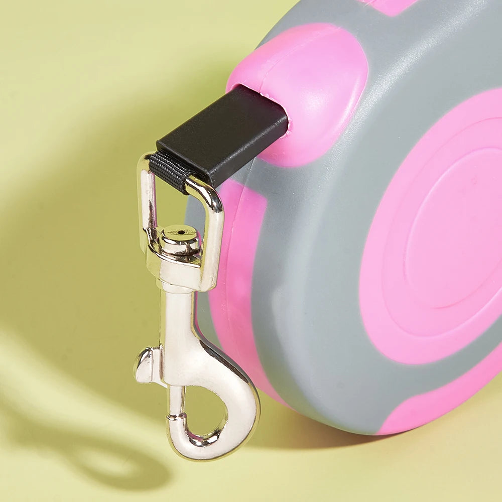 Close-up of a pink and gray dog leash with a gold clip on a yellow background