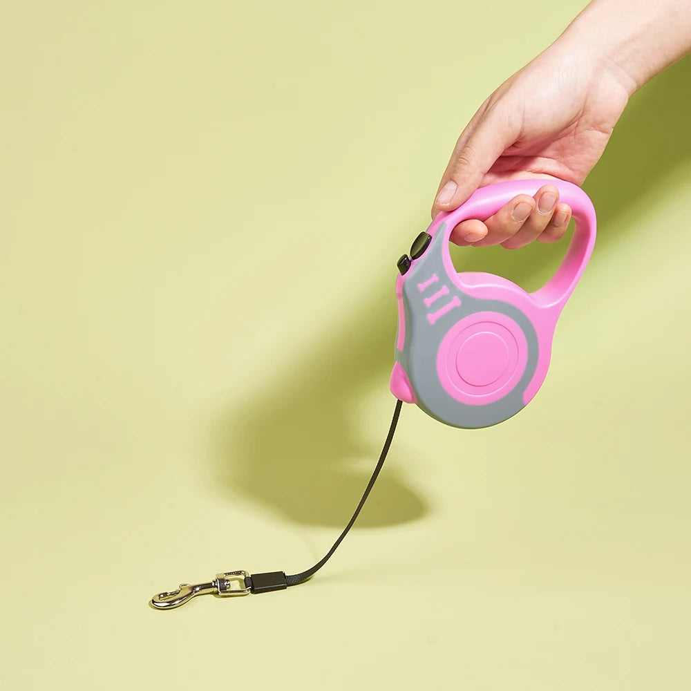 Pink and gray retractable dog leash held by a hand on a light green background