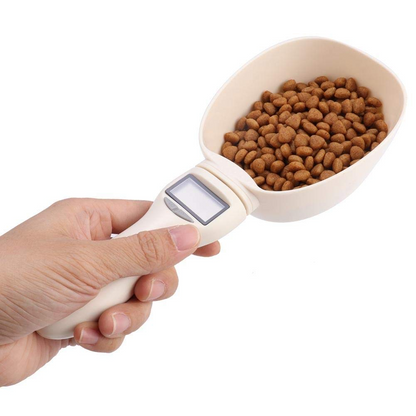 Hand holding a digital pet food scoop with kibble inside on a white background