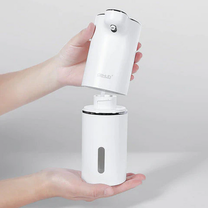 White handheld device with a pump held by a person against a light gray background